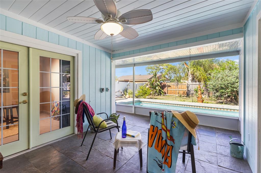 A covered patio with tile flooring overlooks a backyard swimming pool and fenced lawn — 6609 MAUNA LOA BOULEVARD, SARASOTA, FL