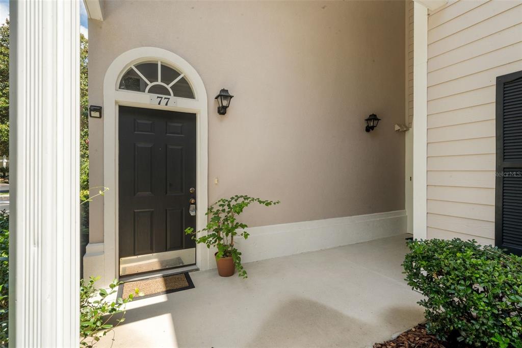A covered entryway features a black front door with a transom window and house number 77 — 10000 SW 52ND AVENUE UNIT 77, GAINESVILLE, FL