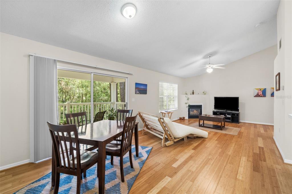 A living and dining area with wood flooring, a fireplace, and a sliding glass door — 10000 SW 52ND AVENUE UNIT 77, GAINESVILLE, FL
