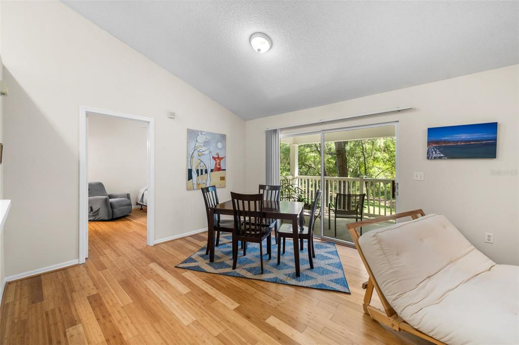 A dining area with a wooden table, blue rug, and sliding glass doors to a balcony — 10000 SW 52ND AVENUE UNIT 77, GAINESVILLE, FL