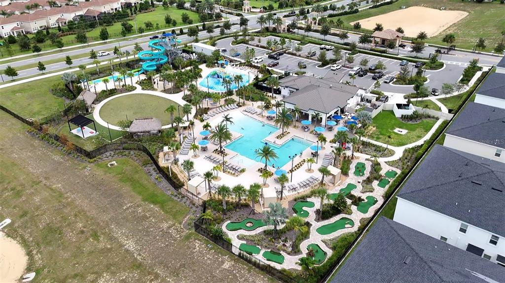 An aerial view shows a community pool area with a waterslide, clubhouse, and putting green — 962 SPLASH SHOT PLACE, DAVENPORT, FL