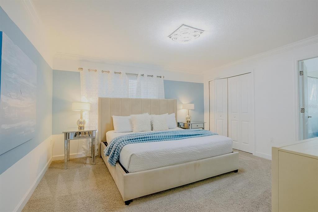 A bedroom features a beige upholstered bed, light blue accent walls, and mirrored nightstands — 962 SPLASH SHOT PLACE, DAVENPORT, FL