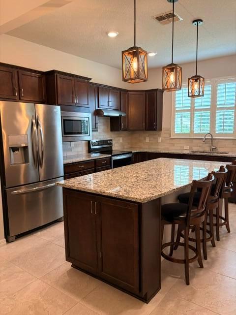 A kitchen features dark wood cabinets, granite countertops, a stainless steel refrigerator, and pendant lighting — 9648 SW 63rd Loop, Ocala FL 34481, OCALA, FL