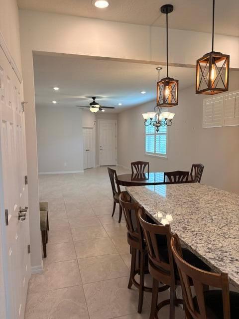 A kitchen island with granite countertops and bar stools overlooks a dining and living area — 9648 SW 63rd Loop, Ocala FL 34481, OCALA, FL