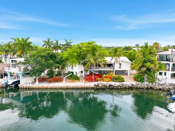An aerial view shows a white waterfront house with a boat dock and palm trees — 154 Redwing Rd, Tavernier FL 33070, TAVERNIER, FL