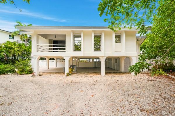 A two-story house with a raised living level, white exterior, and an open ground-level carport — 154 Redwing Rd, Tavernier FL 33070, TAVERNIER, FL