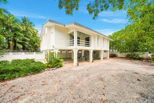 A two-story house elevated on concrete pillars with a white exterior and a balcony — 154 Redwing Rd, Tavernier FL 33070, TAVERNIER, FL