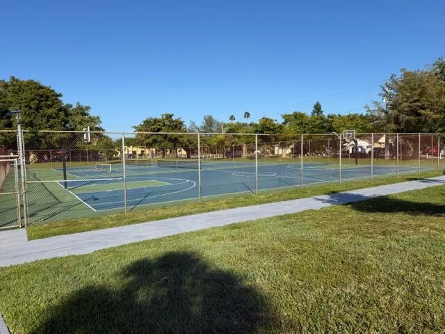 A fenced outdoor basketball court sits adjacent to a grassy lawn under a clear sky — 4357 NW 6 Avenue, Deerfield Beach FL 33064, DEERFIELD BEACH, FL