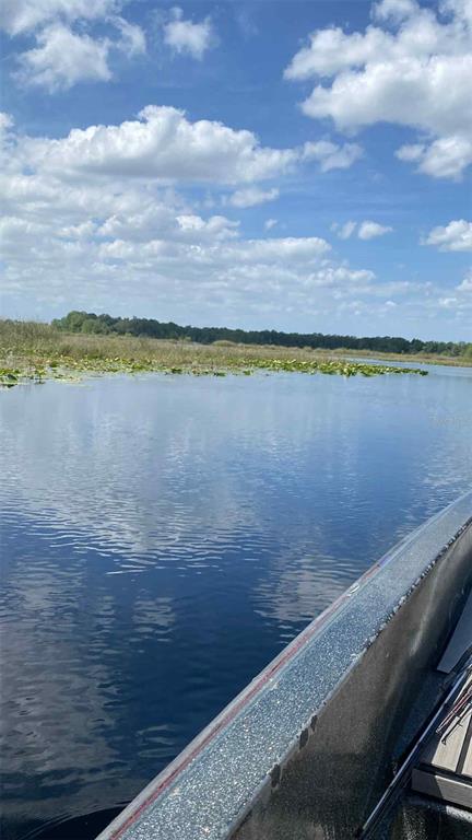 A view from a boat looking across a calm lake toward a distant treeline — 1135 N JACKADEE POINT, INVERNESS, FL