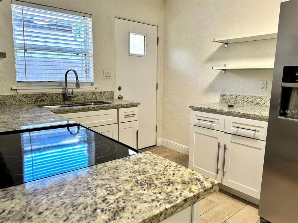 A kitchen features white cabinets, granite countertops, a stainless steel refrigerator, and a window — 2510 BOYD AVENUE UNIT B, ORLANDO, FL