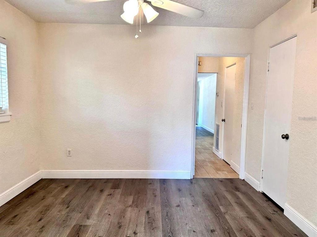 A bedroom with wood-look flooring, a ceiling fan, and a doorway leading to a hallway — 2510 BOYD AVENUE UNIT B, ORLANDO, FL