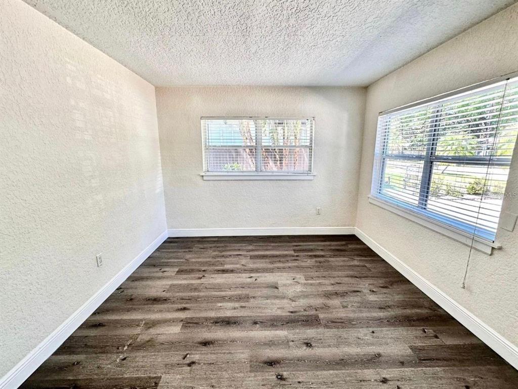 An empty room features wood-look flooring, white walls, and two windows with blinds — 2510 BOYD AVENUE UNIT B, ORLANDO, FL
