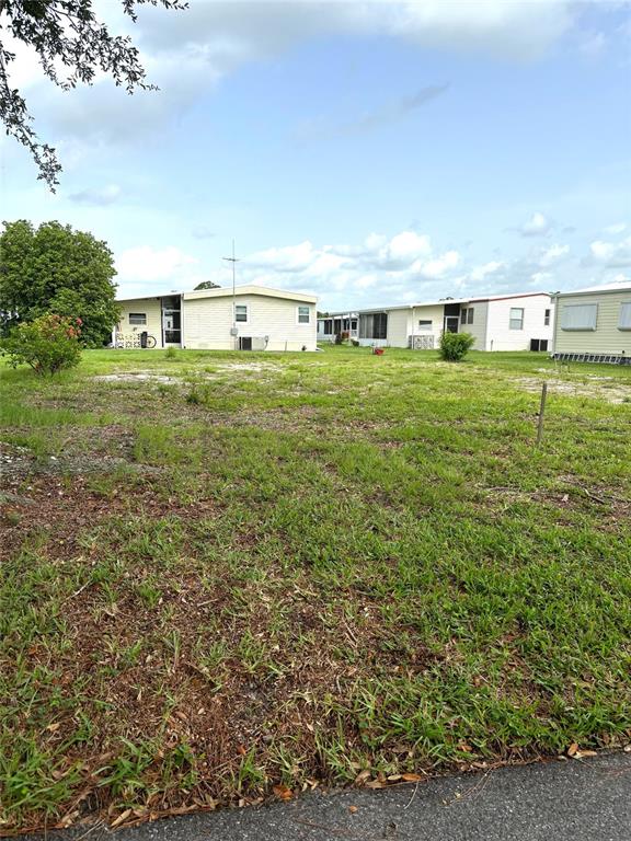 A vacant grassy lot sits in front of several manufactured homes under a blue sky — 236 EL PRADO, NORTH PORT, FL