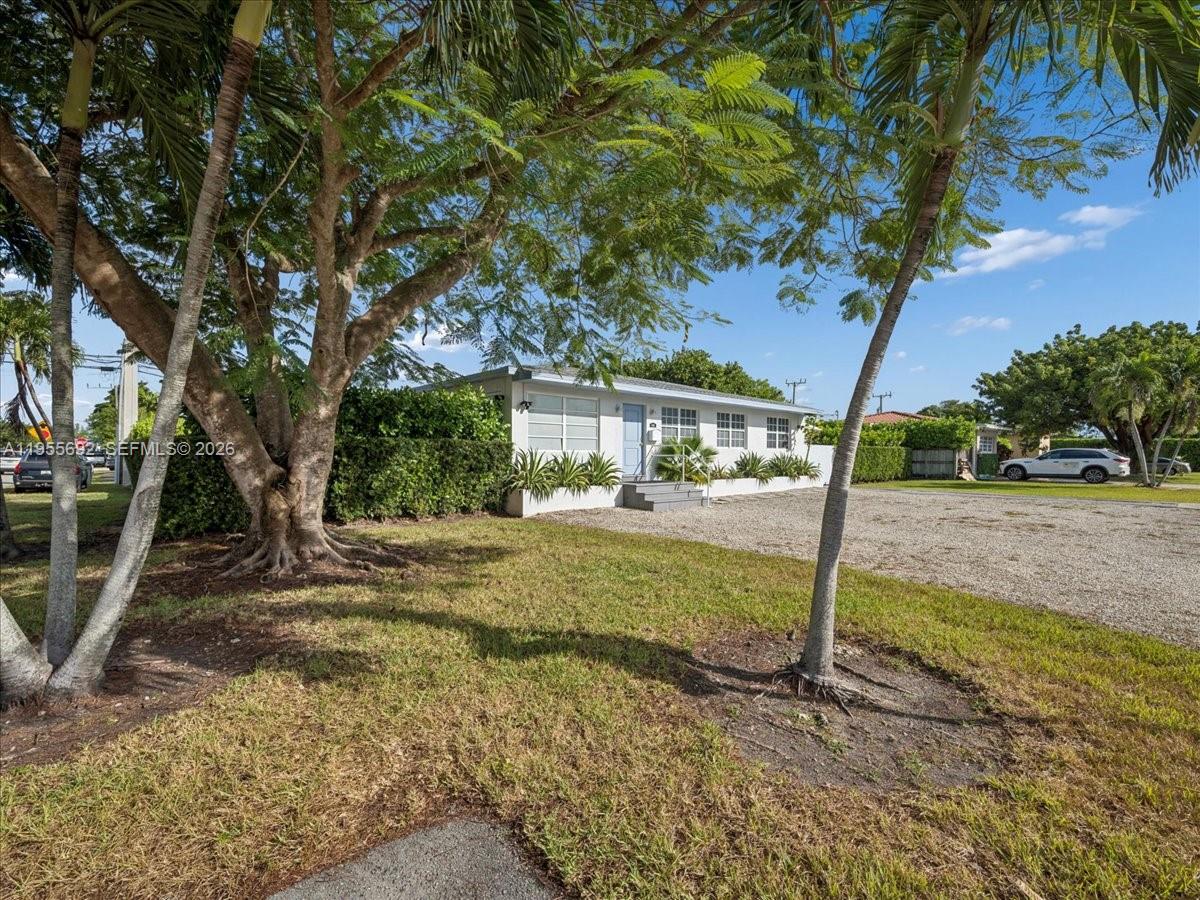 A single-story house with a gravel driveway sits behind large trees and a hedge — 6891 SW 26th Ter, Miami FL 33155, MIAMI, FL