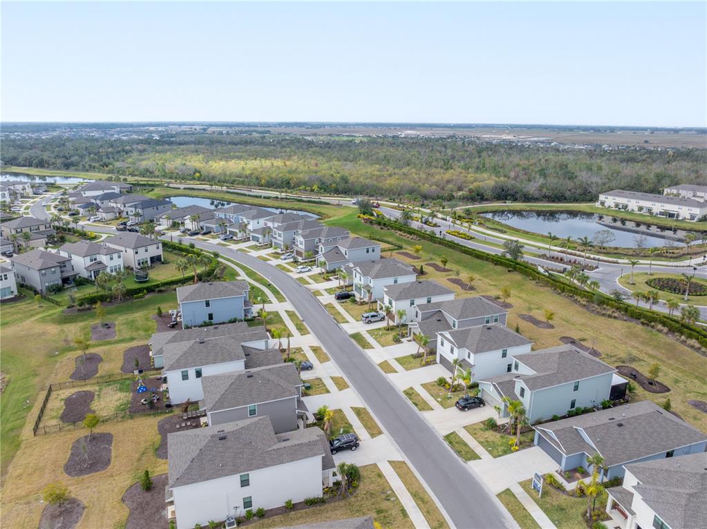 An aerial view shows a suburban neighborhood with houses, a winding road, and retention ponds — 9076 TEQUILA SUNRISE DRIVE, SARASOTA, FL