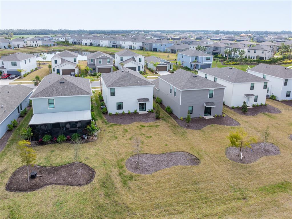 An aerial view shows the backyards of several suburban houses with small trees and landscaping — 9076 TEQUILA SUNRISE DRIVE, SARASOTA, FL