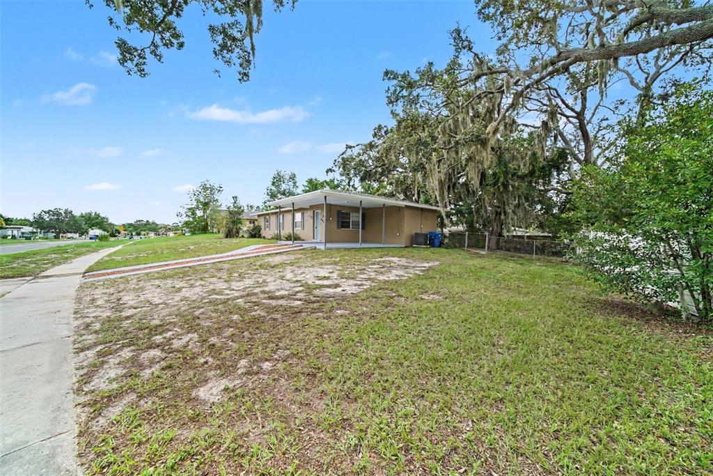 A single-story house with a covered front porch sits on a grassy lot with trees — 6925 TREEHAVEN DRIVE, SPRING HILL, FL