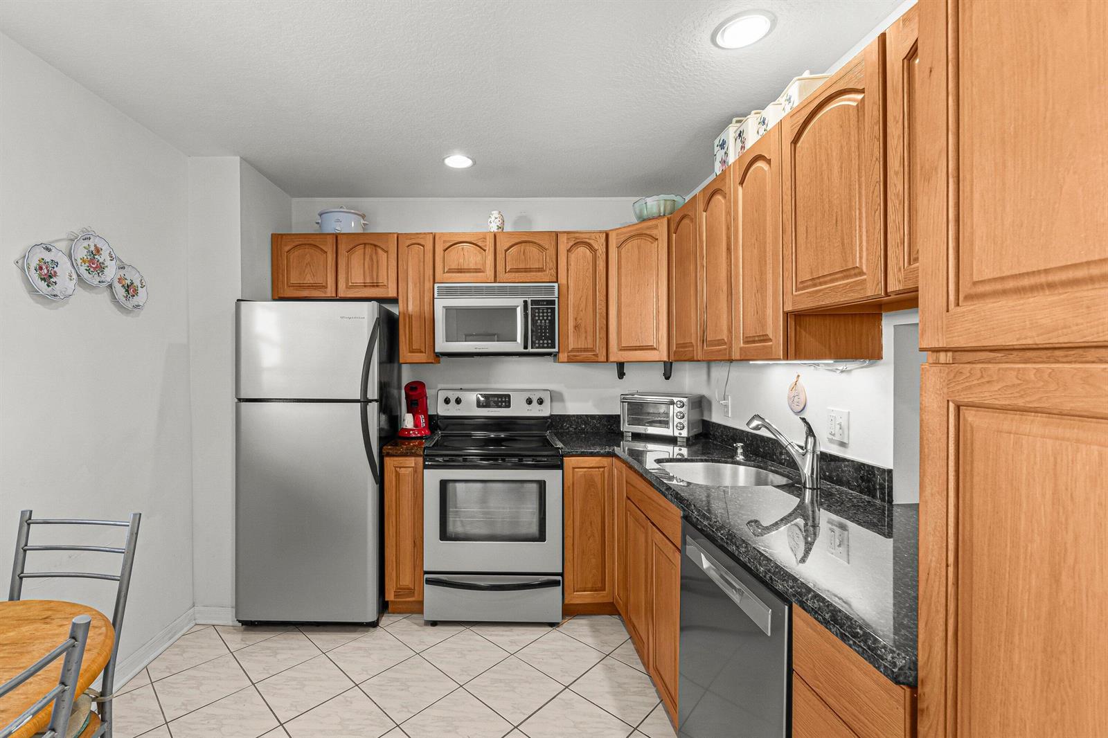 A kitchen features wood cabinets, stainless steel appliances, and dark granite countertops — 2515 NE 1st Court # 4100, Boynton Beach FL 33435, BOYNTON BEACH, FL