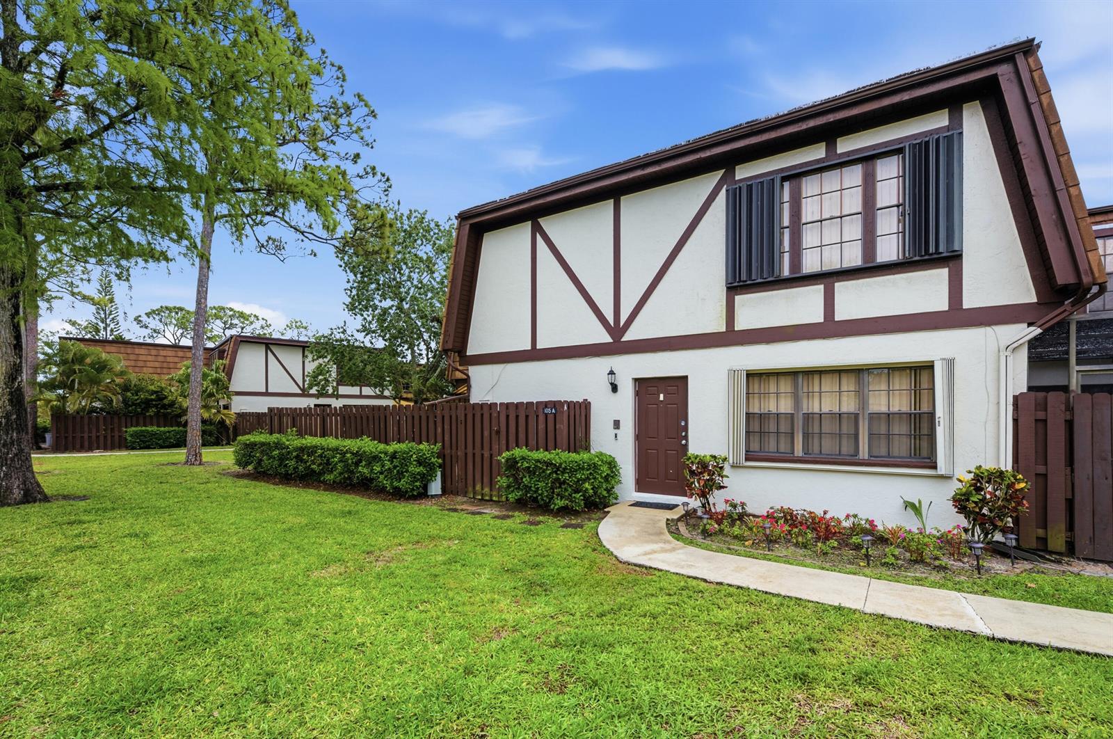 A two-story townhouse with Tudor-style trim, a brown front door, and a concrete walkway — 105 Weybridge Circle # A, Royal Palm Beach FL 33411, ROYAL PALM BEACH, FL