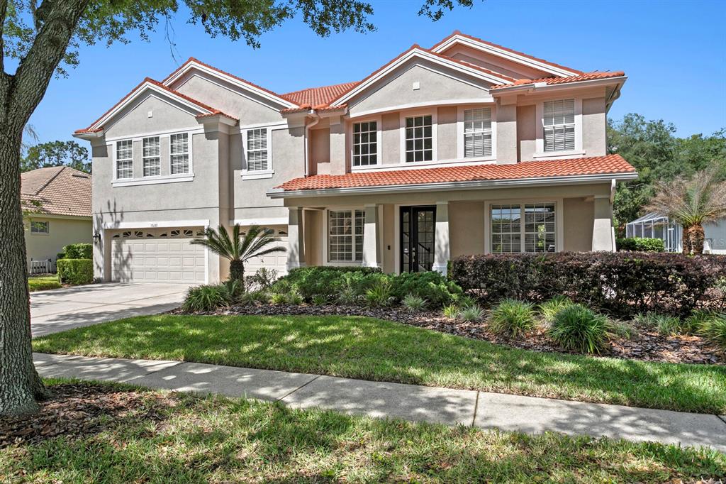 A two-story house with a beige stucco exterior, red tile roof, and a three-car garage — 10235 ESTUARY DRIVE, TAMPA, FL