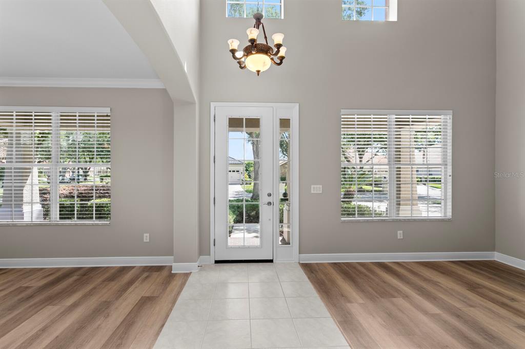 An entryway with a high ceiling, a chandelier, tile flooring, and two windows with blinds — 10235 ESTUARY DRIVE, TAMPA, FL