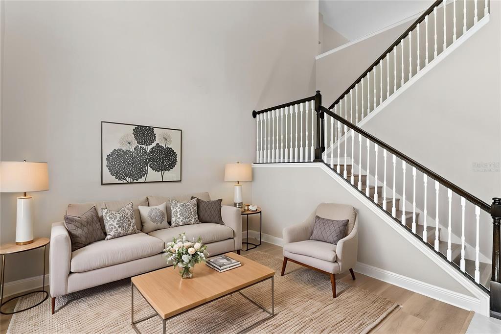A living room features a beige sofa, an armchair, and a staircase with white railings — 10235 ESTUARY DRIVE, TAMPA, FL