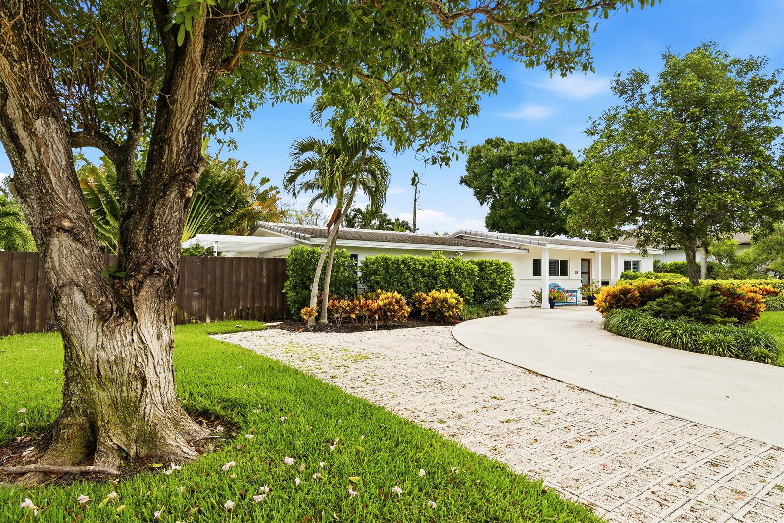 A single-story white house features a concrete driveway, a gravel path, and lush landscaping — 251 Gregory Place, West Palm Beach FL 33405, WEST PALM BEACH, FL