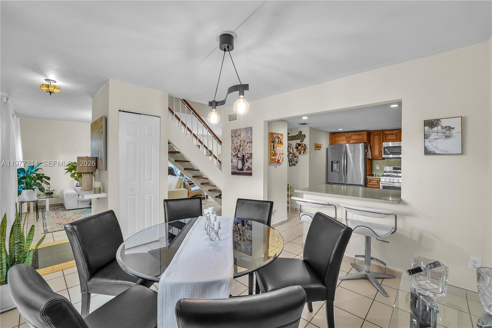 A dining area with a glass table and black chairs sits before a kitchen pass-through — 6639 SW 116th Pl # 1, Miami FL 33173, MIAMI, FL