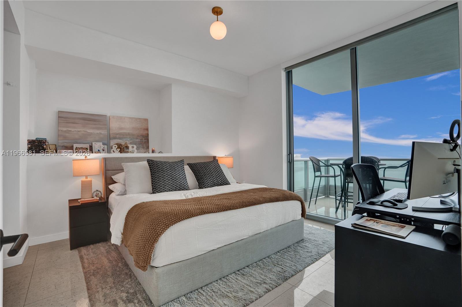 A bedroom features a bed, a desk with a computer, and a balcony with ocean views — 900 Biscayne Blvd # 2907, Miami FL 33132, MIAMI, FL
