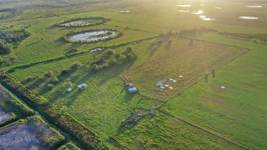 An aerial view shows a rural property with open fields, several ponds, and small structures — 44250 CLAY GULLY ROAD, MYAKKA CITY, FL