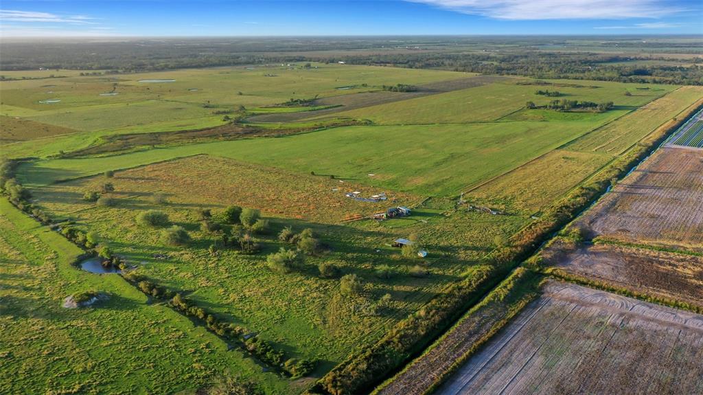 An aerial view shows a large, flat rural property with green pastures and a small structure — 44250 CLAY GULLY ROAD, MYAKKA CITY, FL