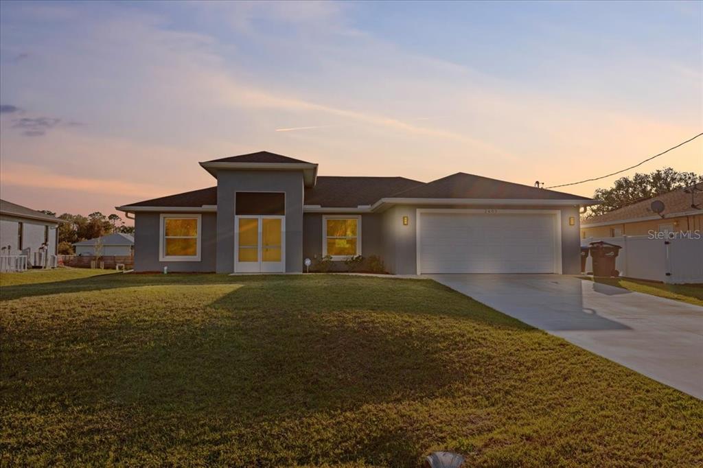 A single-story house with a gray exterior, a two-car garage, and a large front lawn — 2405 VANCOUVER LANE, NORTH PORT, FL