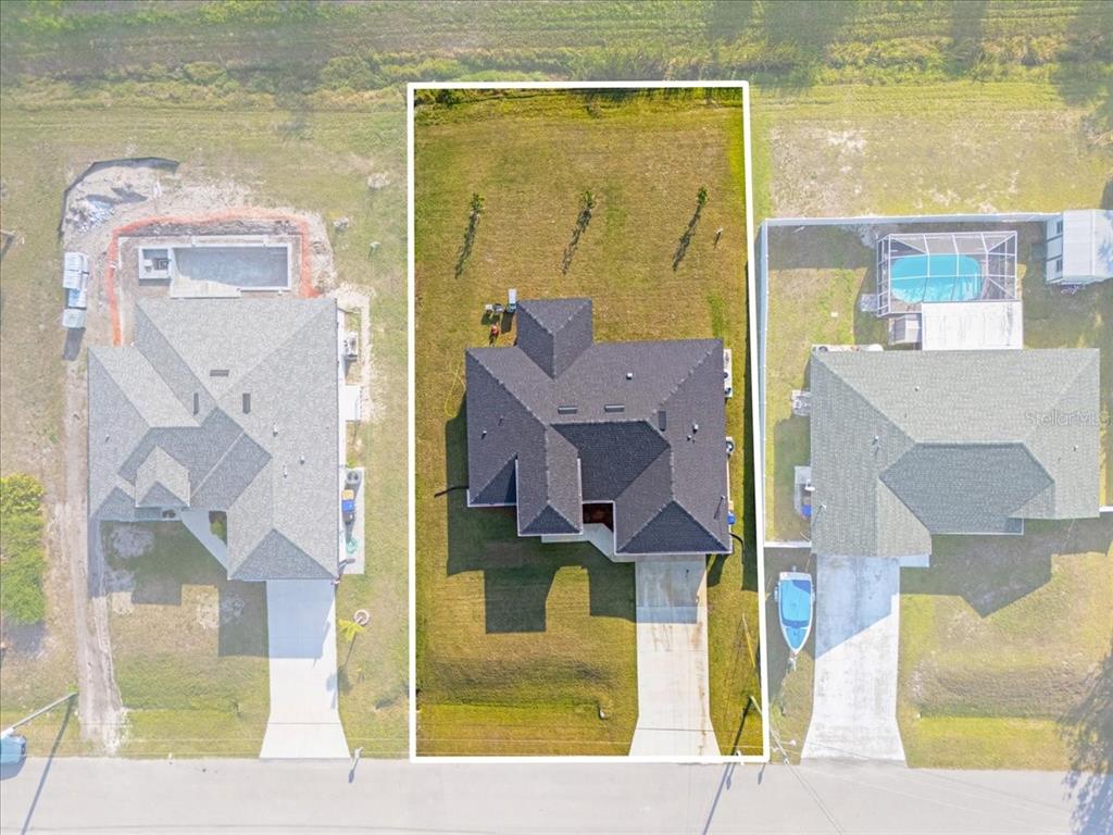 An aerial view shows a house with a dark roof centered between two neighboring properties — 2405 VANCOUVER LANE, NORTH PORT, FL