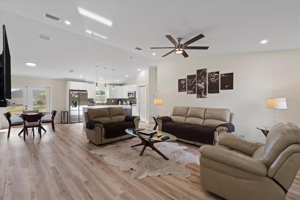 An open-concept living room and kitchen feature light wood flooring and neutral-toned furniture — 2405 VANCOUVER LANE, NORTH PORT, FL
