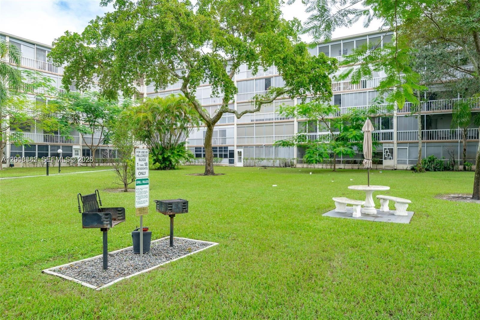 A grassy courtyard features two charcoal grills, a picnic table, and a multi-story apartment building — 950 Hillcrest Dr # 503, Hollywood FL 33021, HOLLYWOOD, FL