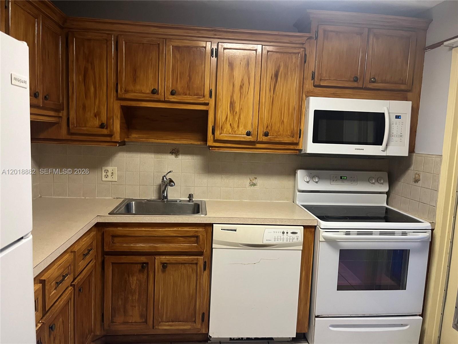 A kitchen features wood cabinets, a white dishwasher, a white stove, and a stainless sink — 950 Hillcrest Dr # 503, Hollywood FL 33021, HOLLYWOOD, FL