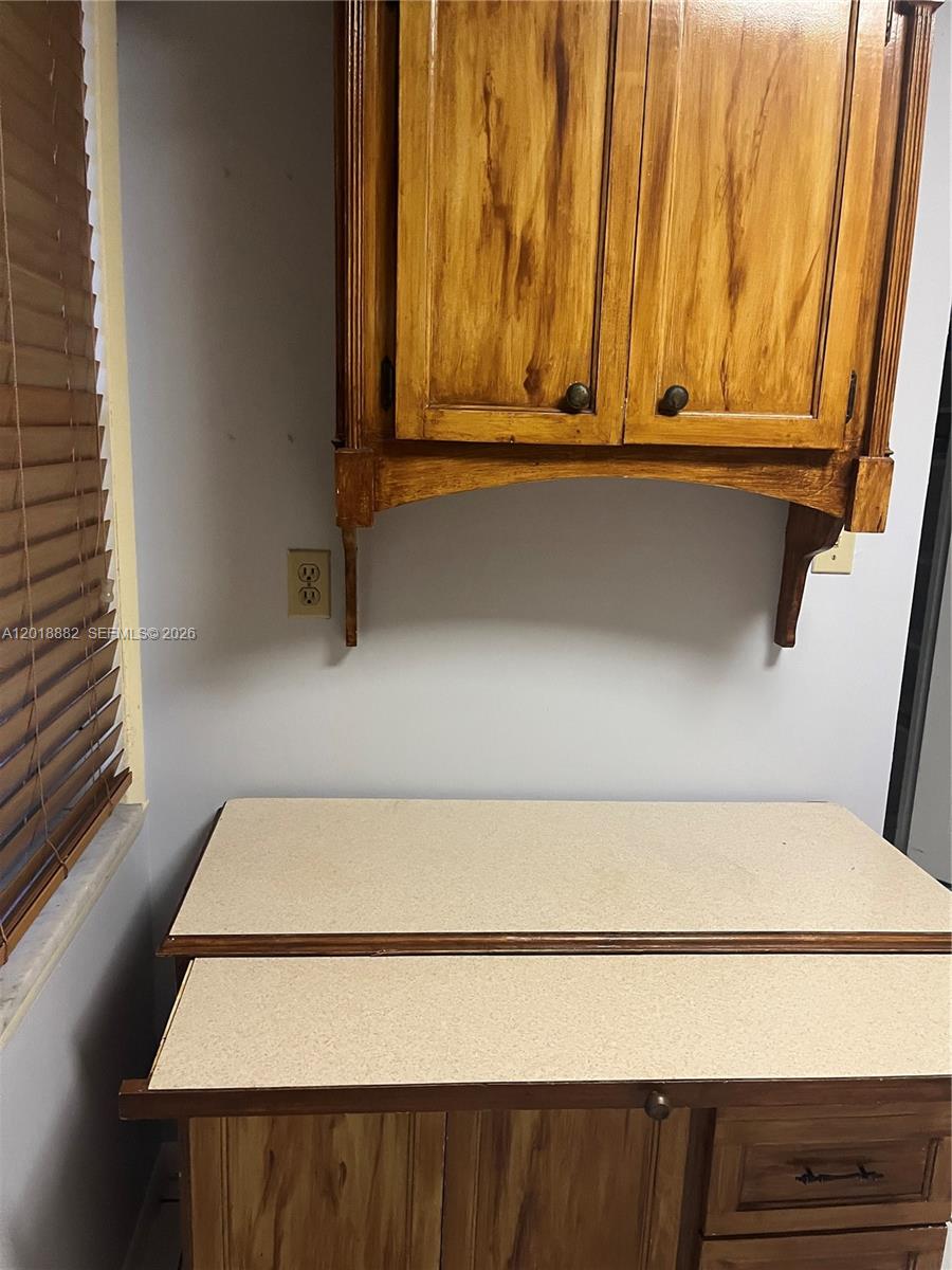 A kitchen area features wooden cabinets, a light-colored countertop, and a wall-mounted electrical outlet — 950 Hillcrest Dr # 503, Hollywood FL 33021, HOLLYWOOD, FL