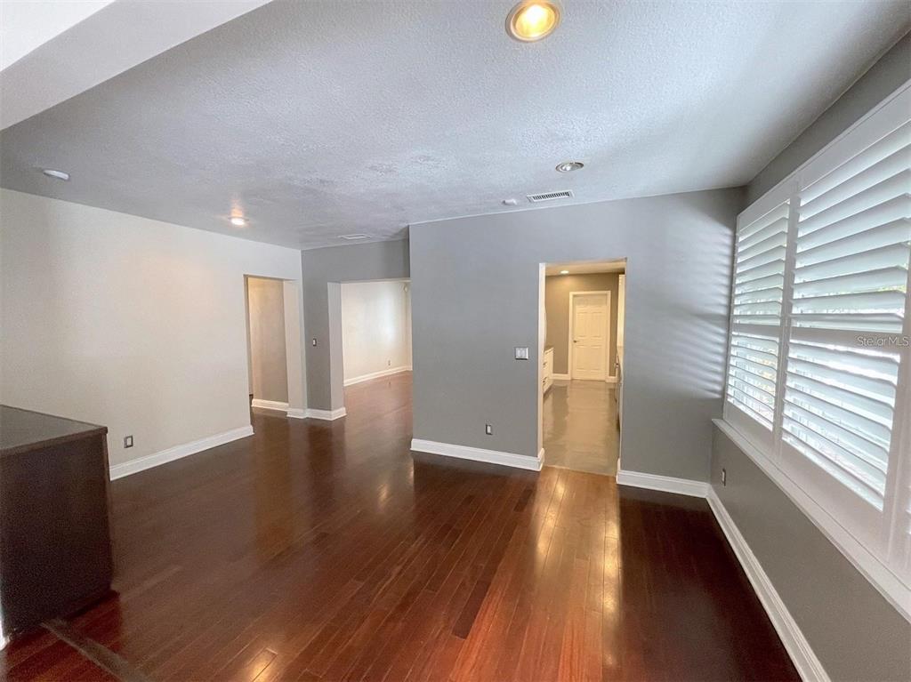An interior room features dark wood flooring, white plantation shutters, and a dark wood bookshelf — 3903 W CORONA STREET, TAMPA, FL