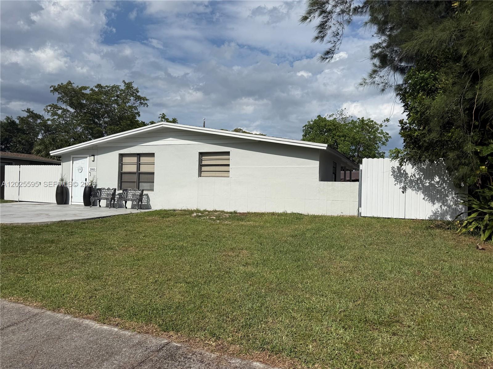 A single-story white house features a front lawn, a concrete patio, and white privacy fencing — 3900 SW 60th Ave, Davie FL 33314, DAVIE, FL