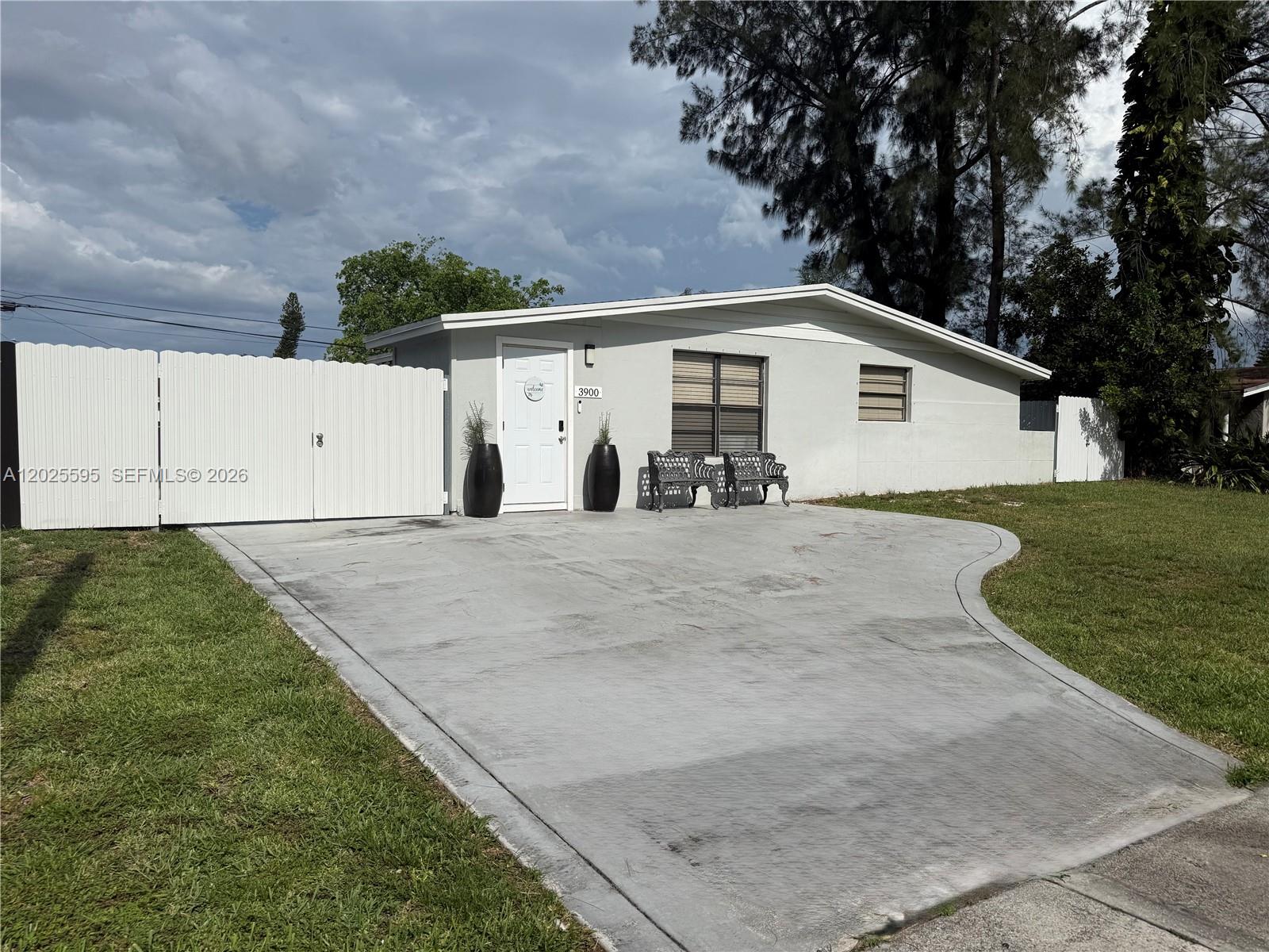 A single-story house with a white fence, concrete driveway, and two benches in front — 3900 SW 60th Ave, Davie FL 33314, DAVIE, FL