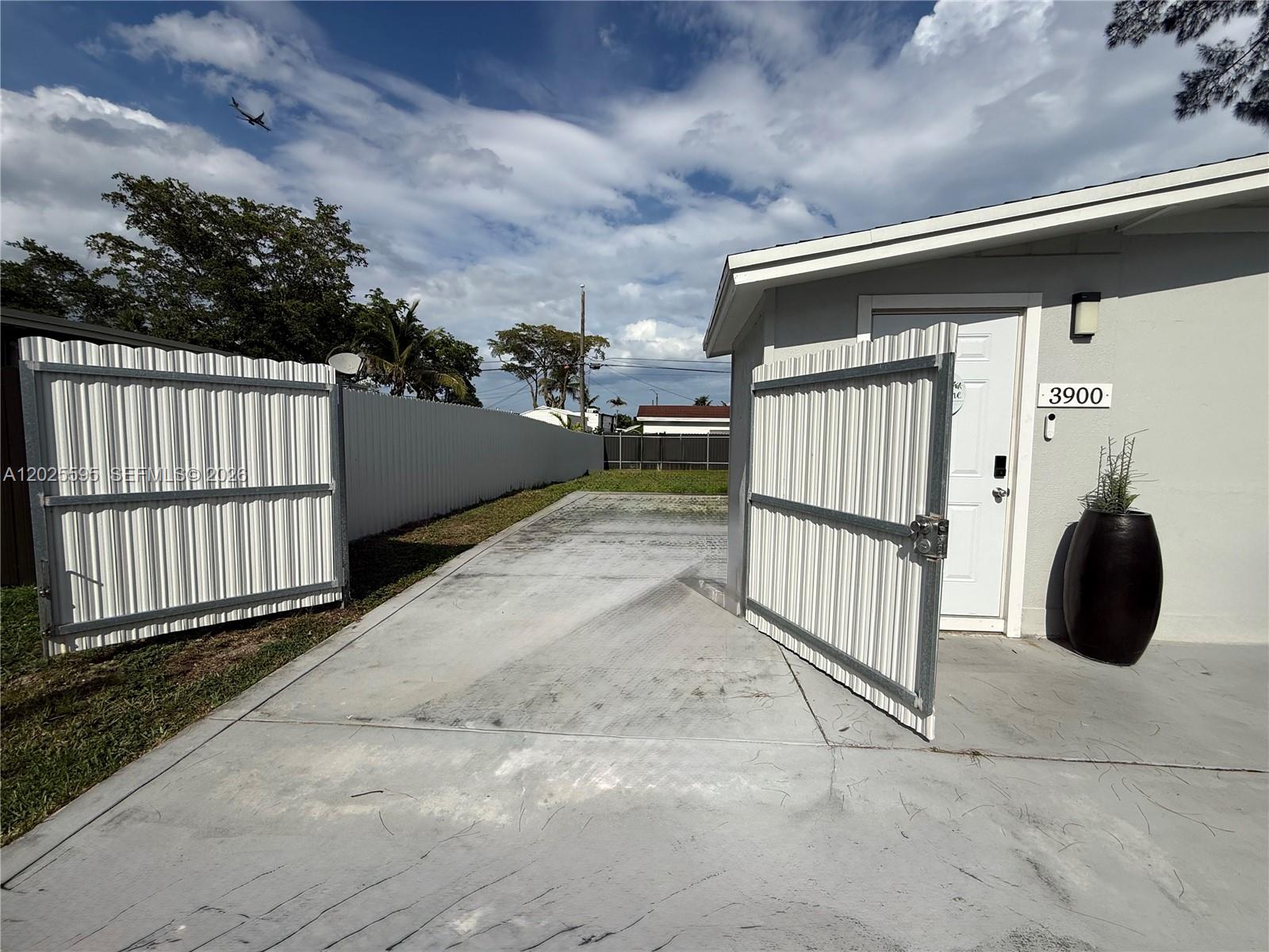 A concrete driveway leads to a white door with a metal gate and fence — 3900 SW 60th Ave, Davie FL 33314, DAVIE, FL