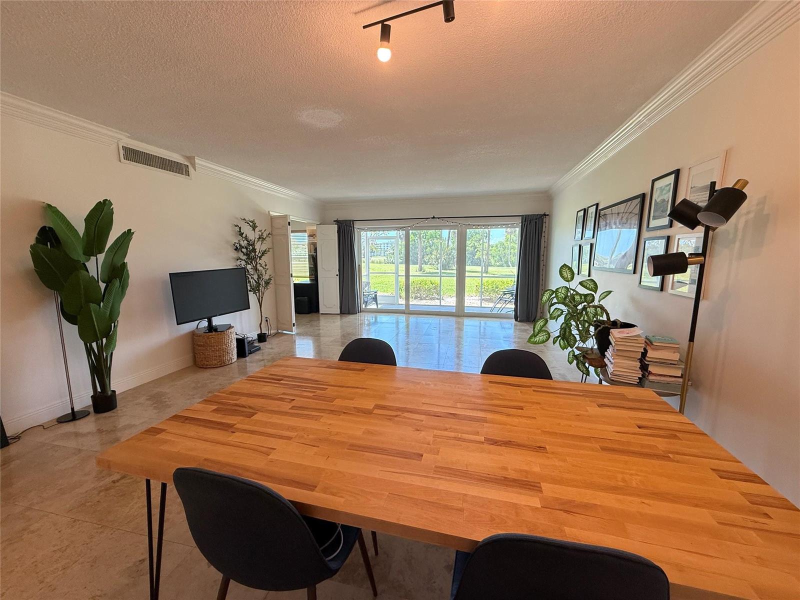 A dining area with a wooden table leads to a living space with sliding glass doors — 3000 N Palm Aire Drive # 107, Pompano Beach FL 33069, POMPANO BEACH, FL