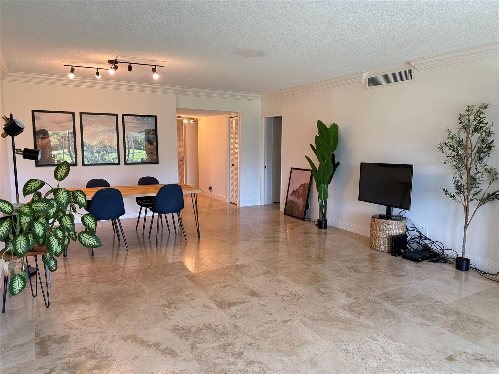 A dining area and living space with tile floors, track lighting, and potted plants — 3000 N Palm Aire Drive # 107, Pompano Beach FL 33069, POMPANO BEACH, FL