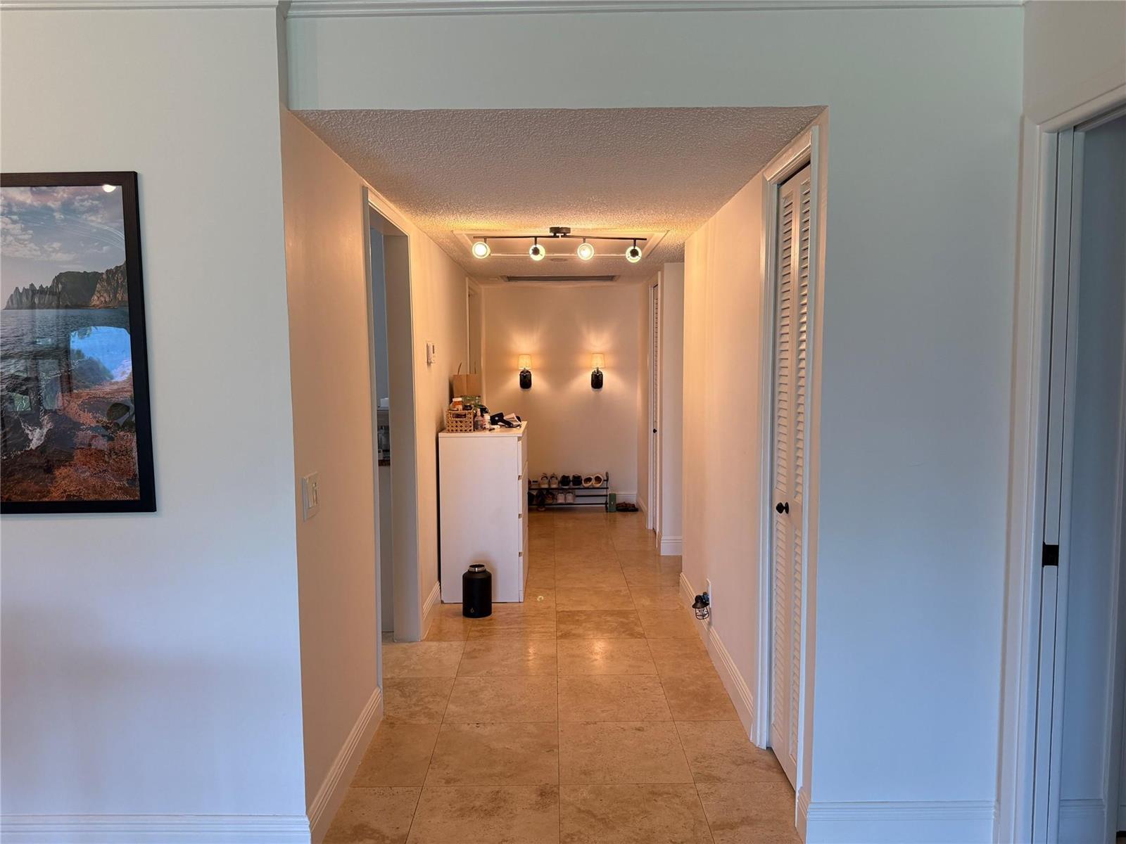 A hallway with tile flooring, a white cabinet, and overhead track lighting — 3000 N Palm Aire Drive # 107, Pompano Beach FL 33069, POMPANO BEACH, FL