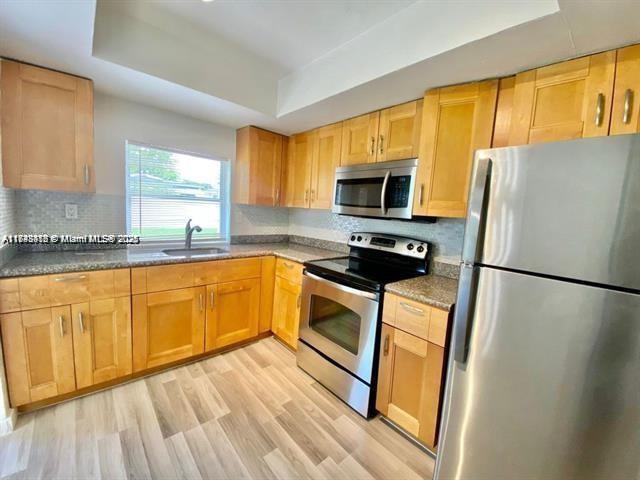 A kitchen features light wood cabinets, stainless steel appliances, and light-colored wood-look flooring — 6521 NW 21st St, Sunrise FL 33313, SUNRISE, FL