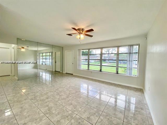 A living room with light-colored tile flooring, a ceiling fan, and large windows — 6521 NW 21st St, Sunrise FL 33313, SUNRISE, FL