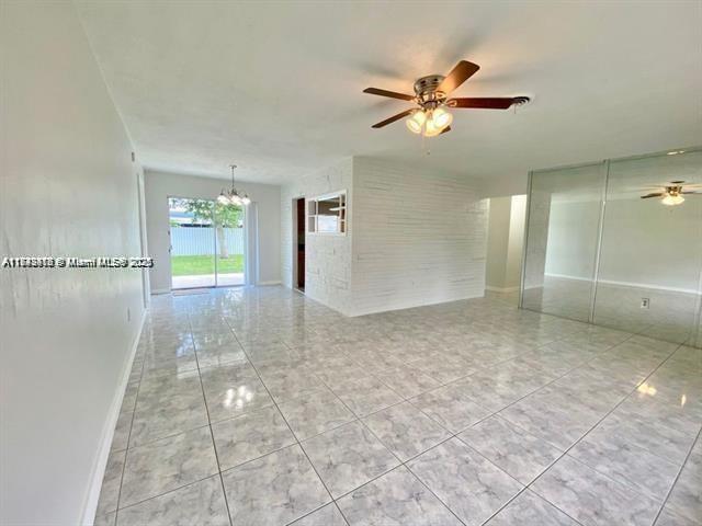 A bright living room with white tiled floors, a ceiling fan, and a brick accent wall — 6521 NW 21st St, Sunrise FL 33313, SUNRISE, FL