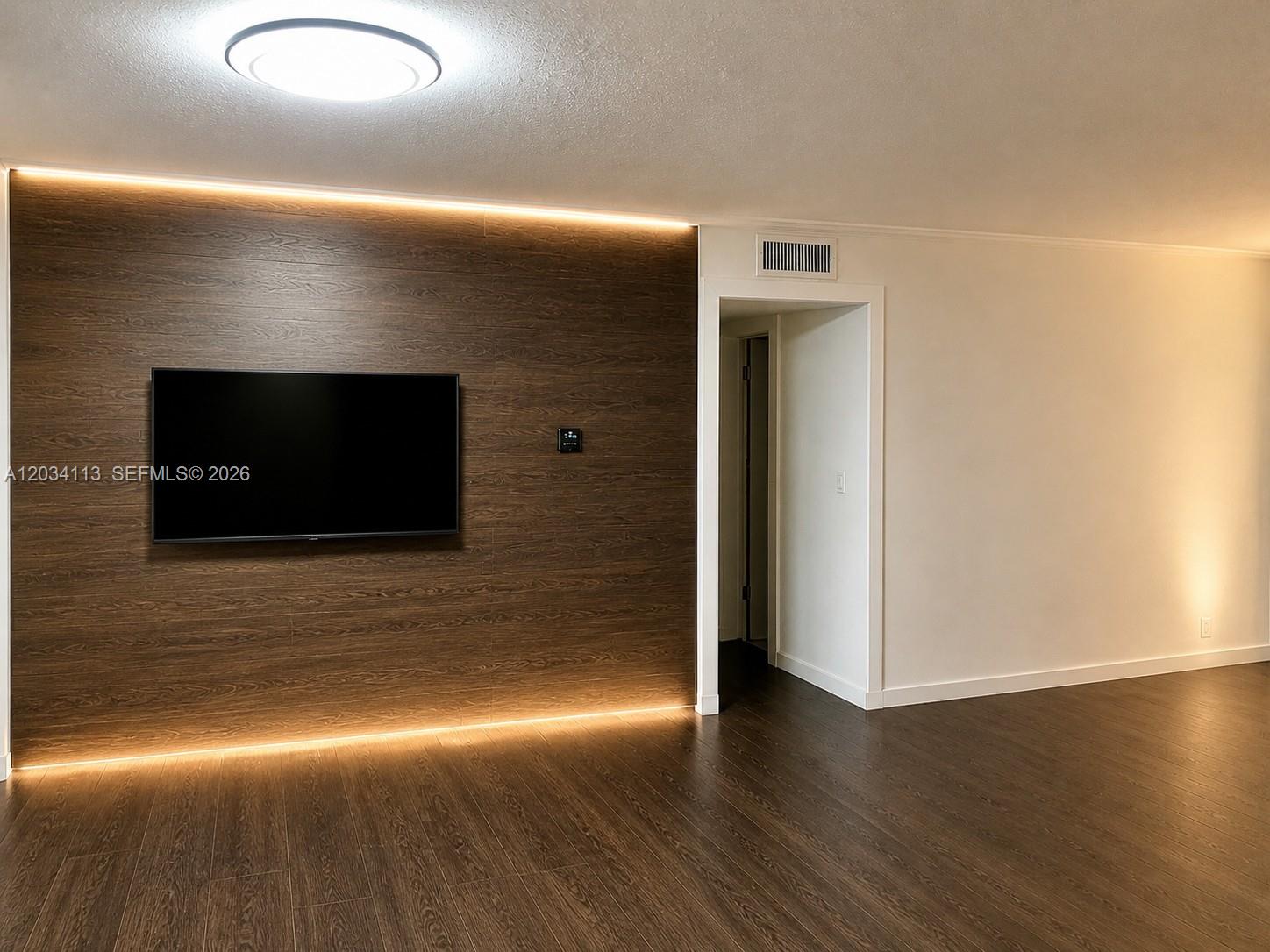 A room features a wood-paneled accent wall with integrated lighting and a mounted television — 180 NE 12th Ave # 16E, Hallandale Beach FL 33009, HALLANDALE BEACH, FL