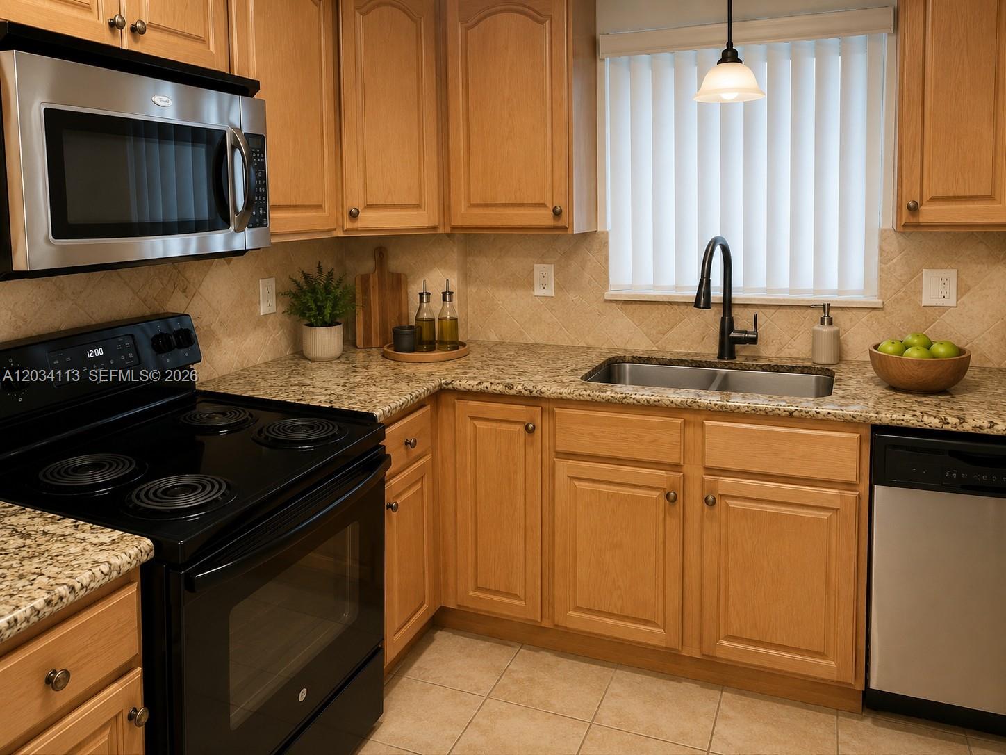 A kitchen with light wood cabinets, granite countertops, a black stove, and a stainless sink — 180 NE 12th Ave # 16E, Hallandale Beach FL 33009, HALLANDALE BEACH, FL