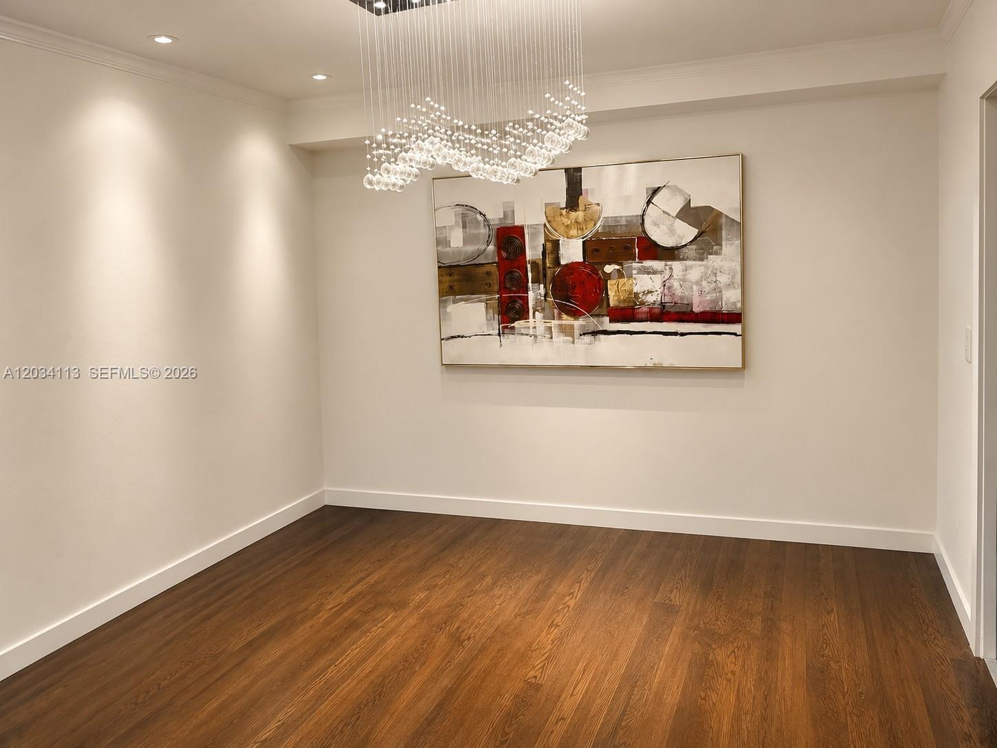 A dining room features dark hardwood floors, white walls, and a modern crystal chandelier — 180 NE 12th Ave # 16E, Hallandale Beach FL 33009, HALLANDALE BEACH, FL